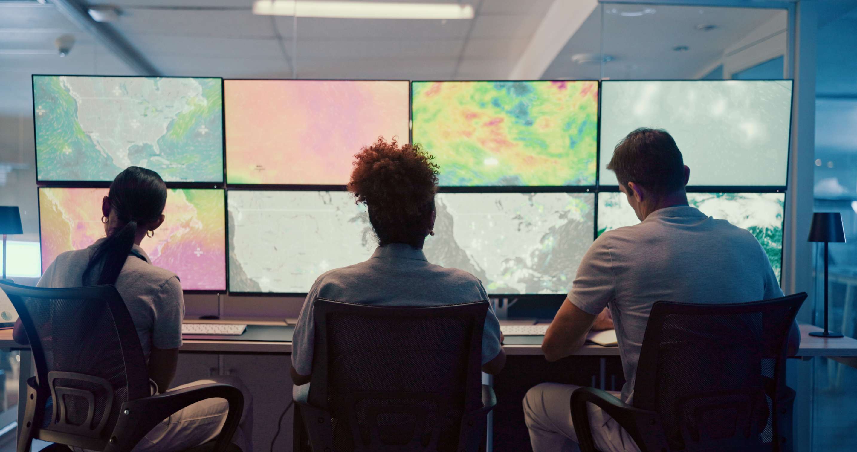 Operations monitoring team in front of multi-screen wall