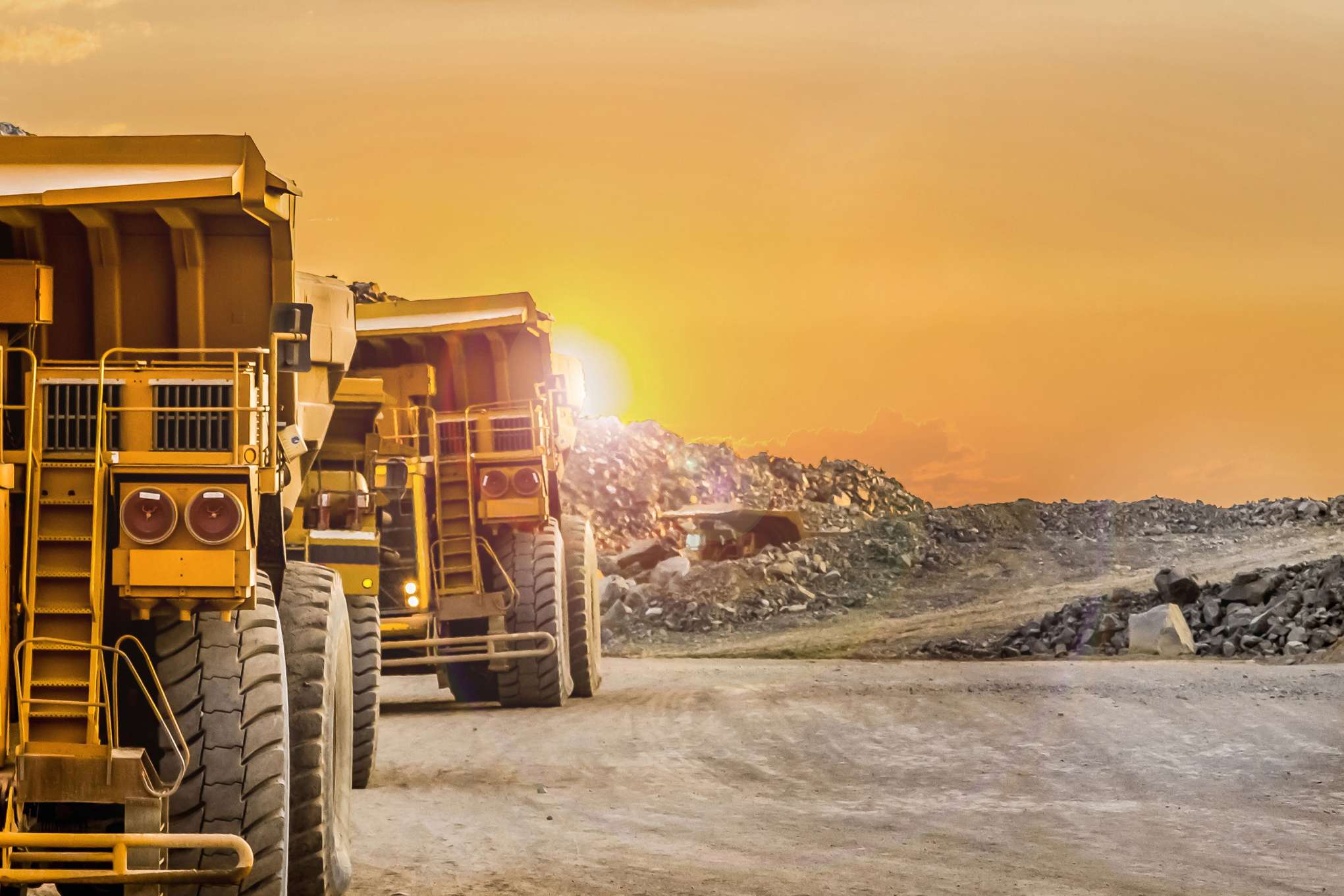 Mining haul trucks at sunset